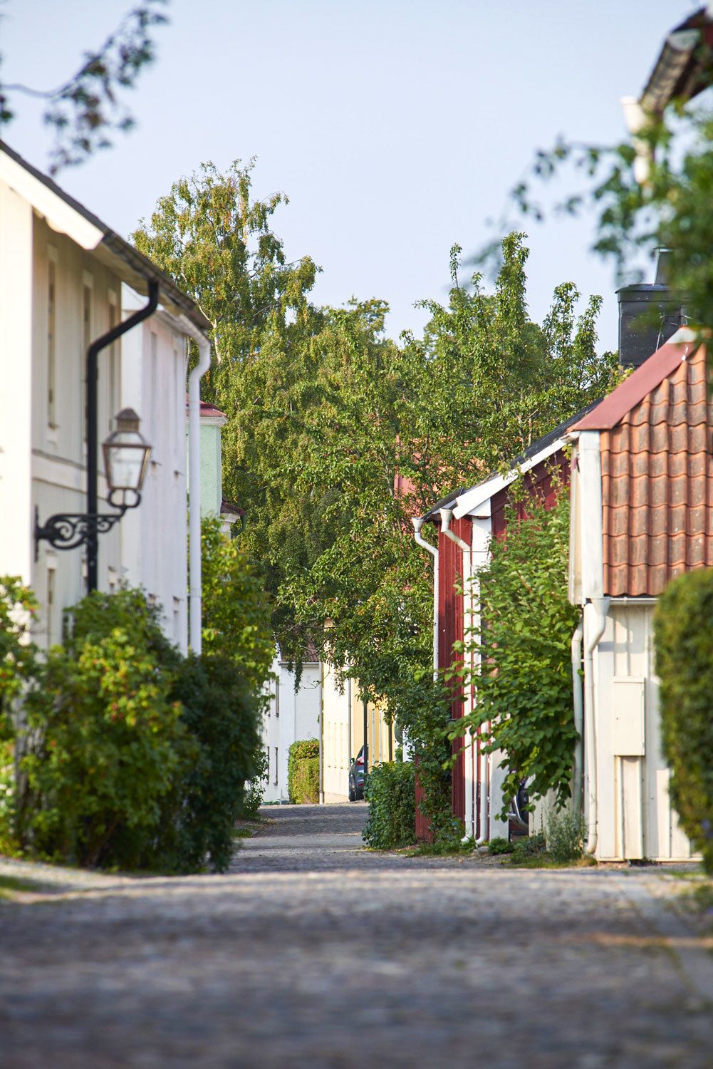 Pittoresk gata med kullersten med vackra trähus i olika färger längst med vägen.
